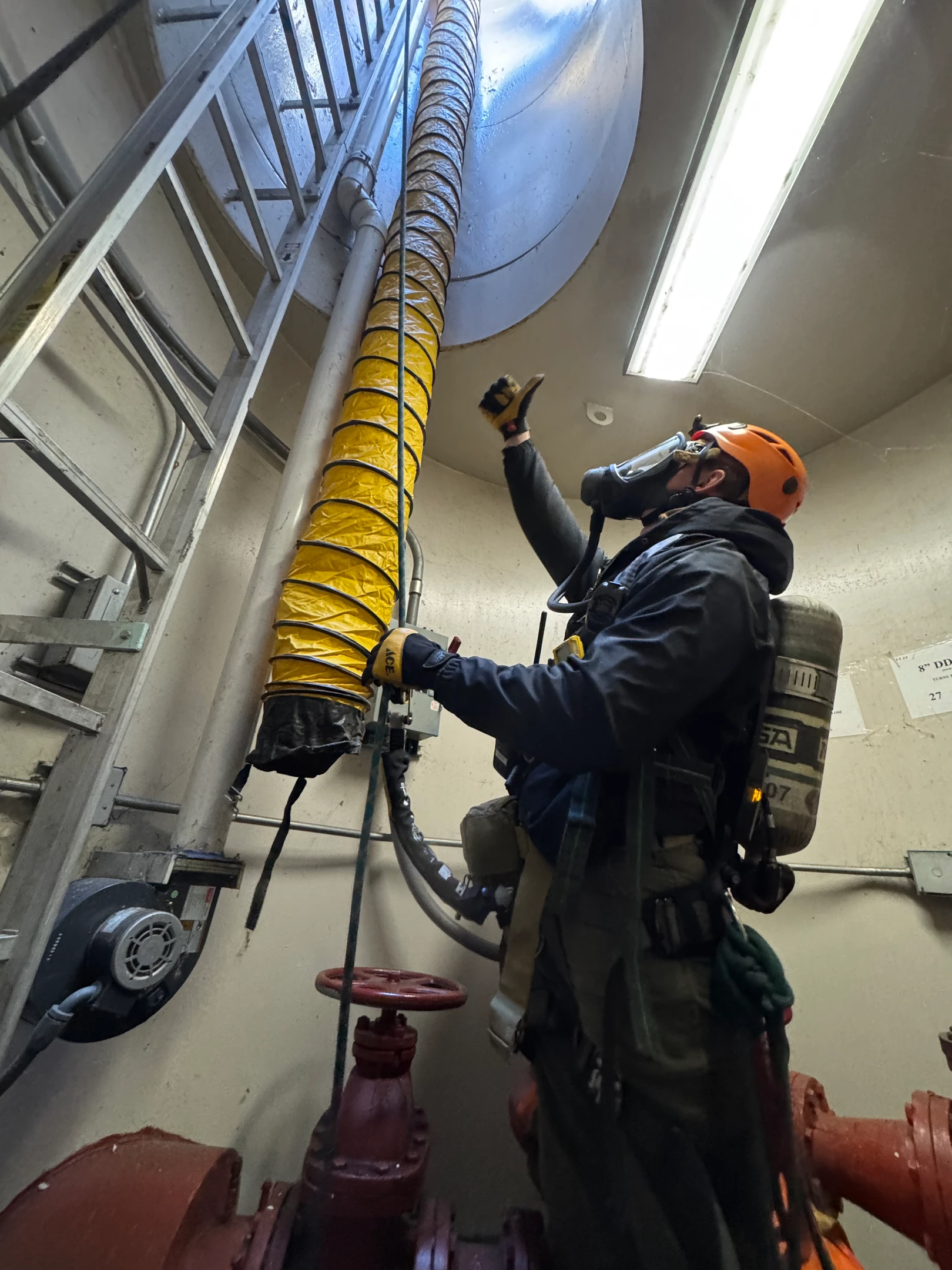 Técnico da CONECT em entrada de espaço confinado, com sistema de proteção respiratória autônoma e ventilação forçada em operação